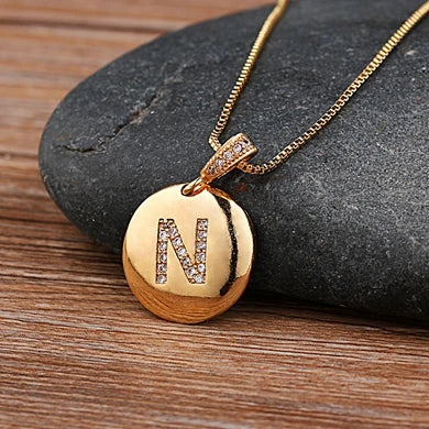 Gold initial letter necklace featuring a 26 A-Z copper charm with CZ accents, styled with a delicate chain from MC The Black Diamonds.