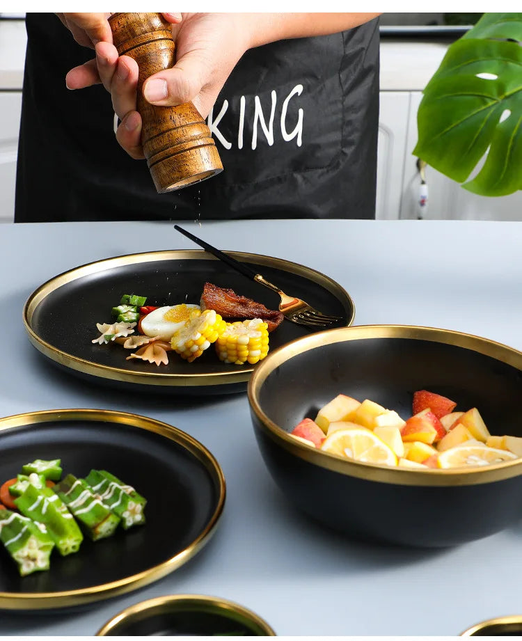 Set of matte gold inlay black porcelain dinnerware by MC THE BLACK DIAMOND, including plates and bowls for elegant kitchen use.