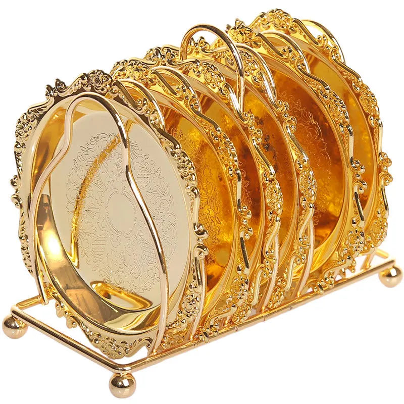 Set of six classical gold metal cocktail coasters with intricate designs, perfect for protecting surfaces in a stylish kitchen setting.