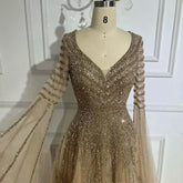 Elegant MC THE BLACK DIAMOND Arabic caramel beaded A-line evening dress with long flowing silhouette and intricate beadwork.