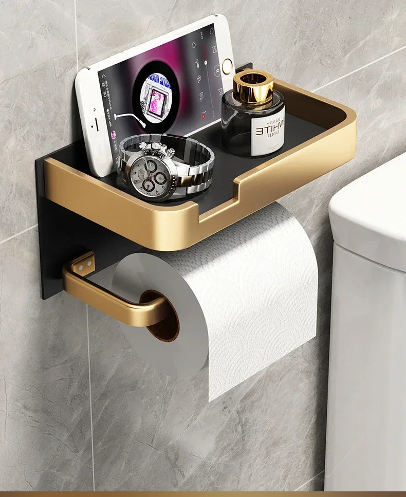 Black gold toilet paper holder by MC THE BLACK DIAMOND mounted on a bathroom wall with a roll of toilet paper.