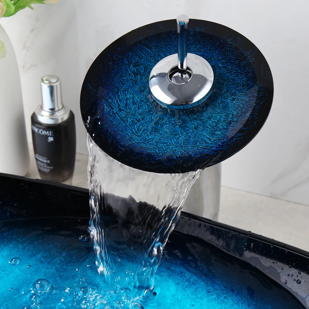 Black waterfall faucet and blue ceramic vessel sink with tempered glass basin, above-counter oval design in a modern bathroom setting.