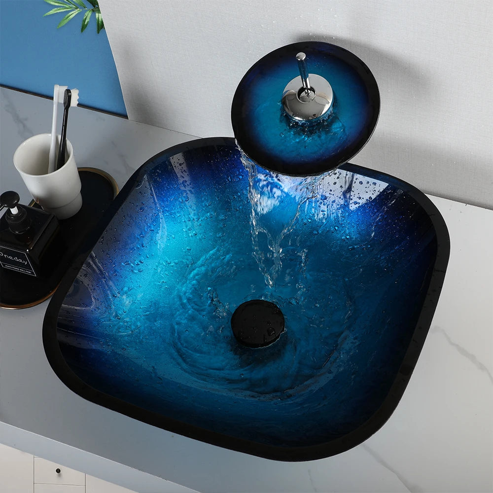 MC THE BLACK DIAMOND ZAPPO tempered glass bathroom vessel sink with black waterfall faucet and oval blue basin, above counter installation.
