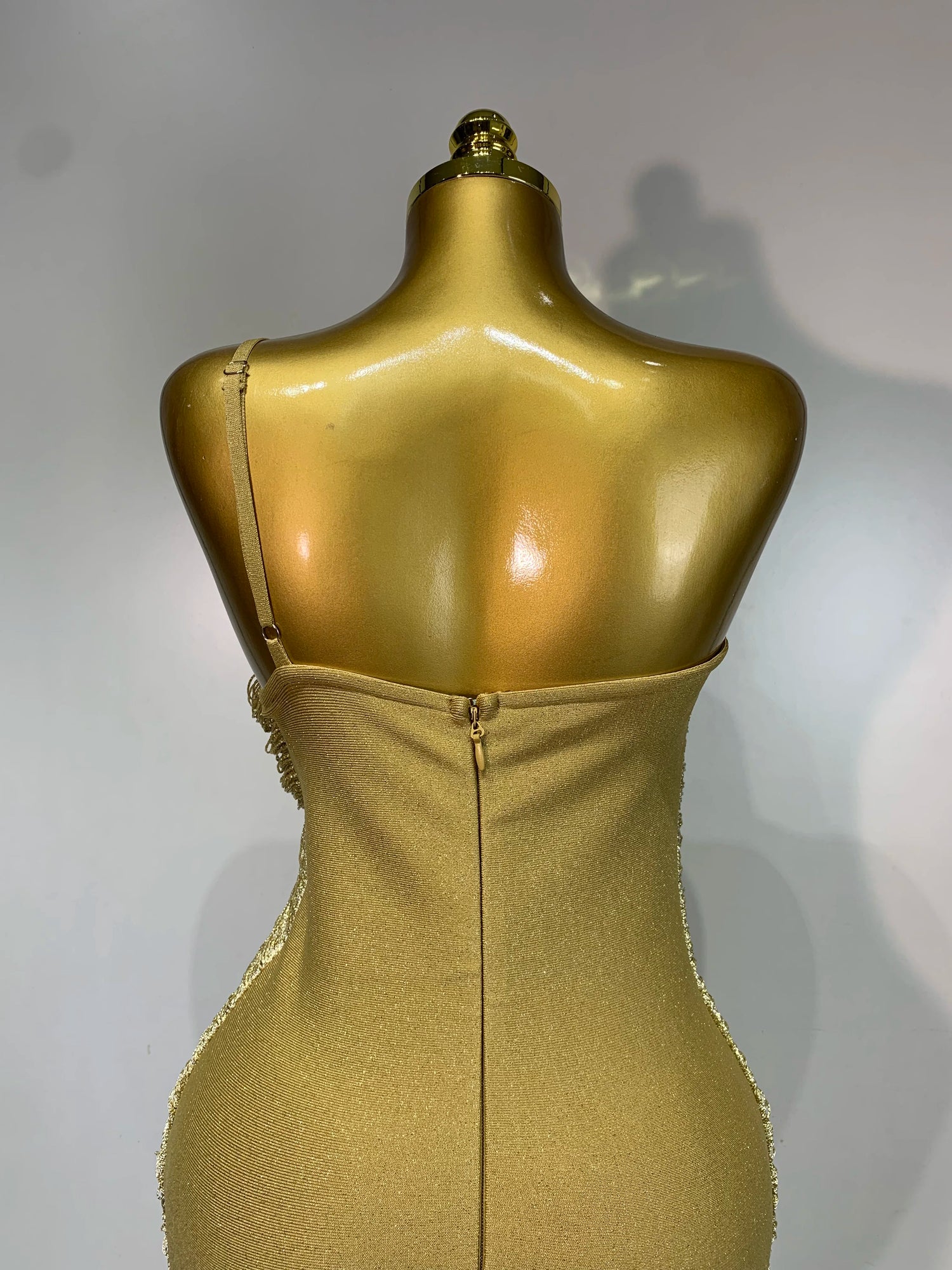 MC Women backless gold bodycon bandage dress with tassel details, designed by MC THE BLACK DIAMOND, showcasing a stylish, fitted silhouette.